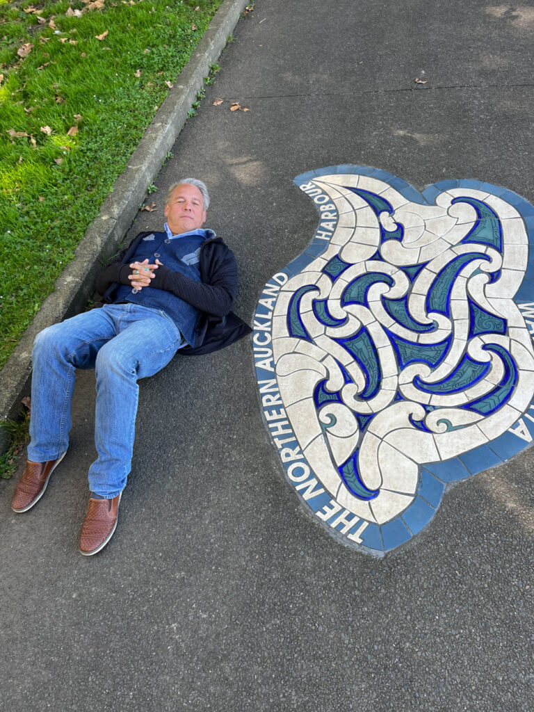 Image of Drew laying on a road next to a inlayed design