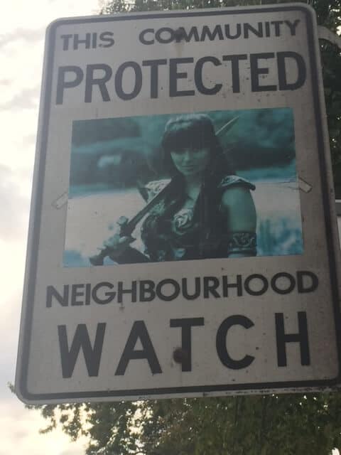 A novelty sign that says "protected neighbourhood watch" with an image of a warrior woman  