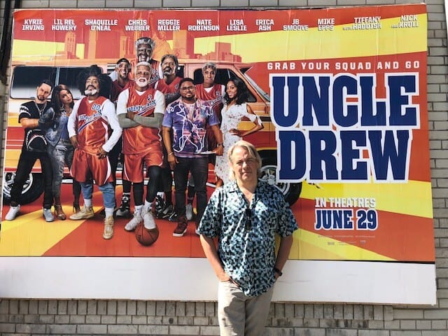 Drew stands in front of a poster for a movie called "Uncle Drew"