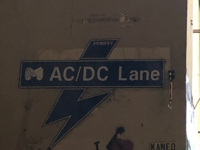 Lightning bolt sign on a wall that reads "AC/DC LANE"