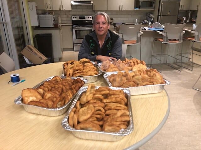 Drew sits at a table with many plates of fried food in front of him