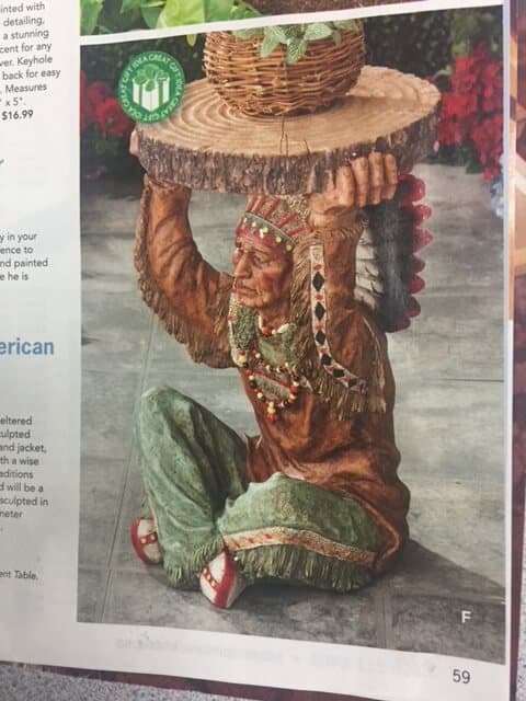 Picture from a catalogue of a kitschy side table with a Chief as the base, holding a wooden slab