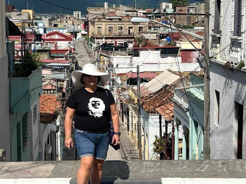 Janine wears a stylish wide brimmed hat and poses in front of a busy street